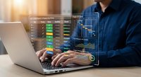 Professional businessman analyzing financial data and trading charts on laptop with holographic interface overlay for investment and market research analysis.