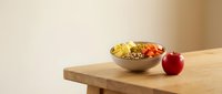 Wooden bowl filled with mixed fresh fruits and nuts on natural wood table with red apple beside, healthy snack and nutrition concept for wellness and diet lifestyle.