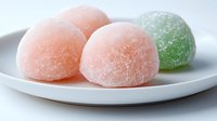 Colorful sugar-coated jelly candies on white plate, sweet confectionery treats in pink and green colors for dessert and snack concepts.