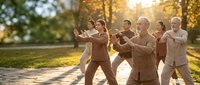 Group of diverse senior adults practicing tai chi together in autumn park during golden hour sunrise creating peaceful wellness exercise scene.