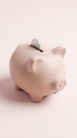Pink ceramic piggy bank with coin slot on pastel background for savings and financial planning concepts.