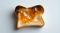Slice of toasted white bread with golden honey drizzle and caramelized edges on light background, overhead view. Isolated food photography for culinary and breakfast concepts.
