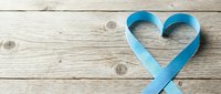 Blue ribbon forming heart shape on rustic wooden background for awareness campaigns and healthcare messaging.