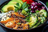 Fresh salmon poke bowl with avocado, cucumber, red cabbage and white rice garnished with black sesame seeds and herbs in dark bowl. Asian cuisine.