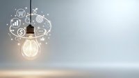 Glowing light bulb with business icons representing innovation, creativity and entrepreneurship concepts on neutral background with copy space.