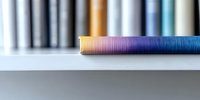 Colorful gradient brush bristles in rainbow colors against blurred background of art supplies. Close-up macro photography shows detailed texture of paintbrush fibers.