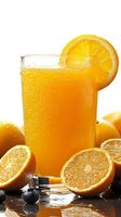Fresh orange juice in glass with condensation drops, garnished with orange slice, surrounded by cut and whole oranges on dark surface with ice cubes.