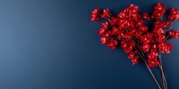 Red artificial cherry blossom branches against dark blue background, creating dramatic contrast for seasonal and festive decorative designs and layouts.