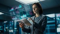Female professional in business attire analyzing digital data analytics and financial charts on tablet in modern office environment with holographic displays and city skyline background.