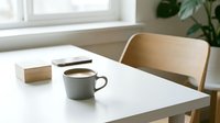 Minimalist workspace with gray mug of coffee, wooden chair, and natural light from window, suitable for business and lifestyle content.