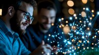 Young Caucasian businessman in glasses analyzing digital network visualization with glowing nodes and connections while collaborating with colleague in dark office.