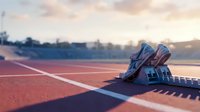 Pair of running shoes placed on athletic track with starting blocks at sunrise, suitable for sports training, fitness marketing, and athletic competition concepts.