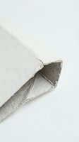 White handmade paper sheet with torn deckle edge curled corner showing texture and fiber detail on clean background for artistic projects.