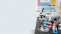 Modern chemistry laboratory workspace with microscope, test tubes, beakers and periodic table chart for scientific research and education.