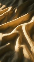 Crumpled tan linen fabric with dramatic shadows and natural light creating depth and texture, suitable for fashion, textile, and design backgrounds.