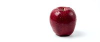 Fresh red apple with water droplets isolated on white background for healthy eating and nutrition concepts.