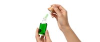 Hands applying green serum with dropper for skincare routine on white background isolated for cosmetic and beauty product design.
