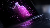 Glowing purple particles burst from laptop screen creating magical digital effect with sparkles and light reflection on keyboard in dark atmosphere.