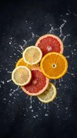 Fresh citrus fruit slices with dynamic water splash on dark background. Orange, lemon and grapefruit creating vibrant composition for healthy lifestyle concepts.