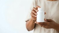 Close-up of hands holding blank white cosmetic bottle for skincare, lotion, or serum product mockup and branding purposes.