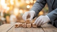Professional businessman arranging wooden blocks with customer service icons on desk. Corporate quality management and client satisfaction concept for business.