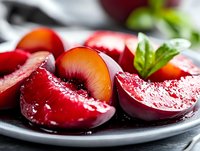 Sliced red plums with fresh mint garnish arranged on a plate, showcasing juicy fruit texture and vibrant colors for food photography and culinary content.