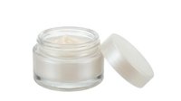 Open jar of white cream with matching lid on white background, isolated cosmetic product for skincare, beauty, and wellness design use.
