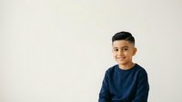 Young boy with dark hair and olive complexion wearing navy blue long-sleeve shirt, smiling at camera against white background. Isolated portrait suitable for educational materials, family websites, and children's content.
