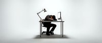 Exhausted businessman sleeping at office desk with laptop and lamp, depicting workplace fatigue and overwork stress in corporate environment.