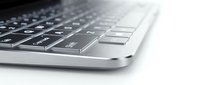Close-up of modern wireless keyboard with black keys and silver aluminum frame on white background, suitable for technology and office design projects.