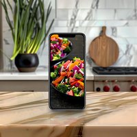Smartphone displaying vibrant fresh salad with vegetables on marble kitchen counter, food photography and social media content creation setup.