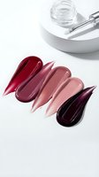 Lipstick color swatches in red pink burgundy shades with glass jar and applicator tool on white background for cosmetic beauty makeup products.
