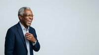Senior African American male professional in dark blazer and light shirt gesturing while speaking, isolated on white background for corporate presentations and business communications.