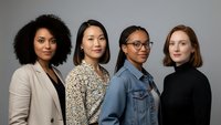 Diverse group of four professional women standing together in studio portrait, representing teamwork, leadership and workplace diversity in modern business.