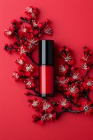 Red liquid lipstick with cherry blossom branches on vibrant red background, flat lay composition for cosmetic and beauty product photography.