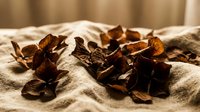 Dried autumn leaves scattered on soft beige linen fabric creating warm seasonal decoration for natural home decor and craft projects.