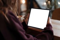 Woman holding tablet with blank white screen in cozy cafe setting. Mockup template for app presentation, digital marketing and technology concepts.