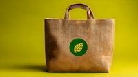 Eco-friendly reusable shopping bag made from natural jute fiber with green leaf logo on yellow background, sustainable lifestyle concept for retail and commerce.