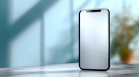 Modern smartphone with blank white screen on marble table with soft window shadows and blurred plant background, mockup for app design presentation.
