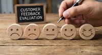 Business professional evaluating customer satisfaction with wooden emoji faces from sad to happy, representing feedback assessment and service quality improvement.