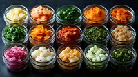 Colorful variety of pickled and fermented vegetables, kimchi, and preserved foods in glass jars arranged in rows on dark background for Asian cuisine.