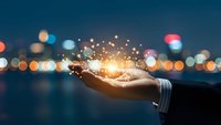 Business professional hand holding glowing light particles with bokeh city lights background at night representing innovation and technology concepts.