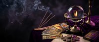 Mystical fortune telling scene with tarot cards, crystal ball, candle and incense smoke creating atmospheric divination setup for spiritual guidance.