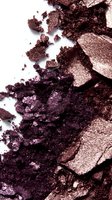 Crushed metallic purple and bronze eyeshadow powder texture on white background, macro shot showing shimmer and pigment details for cosmetic and beauty content.