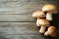 Fresh brown champignon mushrooms on rustic wooden background with copy space. Natural organic food photography for restaurant menu or cooking blog.