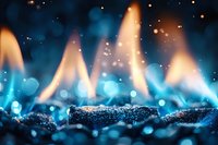 Magical blue flames dancing over dark stones with glowing bokeh lights and sparks creating mystical atmosphere. Artistic macro photography for spiritual concepts.