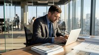 Professional businessman in suit working on laptop in modern glass office with city skyline view, corporate executive at desk analyzing data and documents.