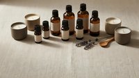 Amber glass bottles with essential oils, candles and dried lavender on linen background for aromatherapy and natural wellness spa treatments.