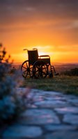 Silhouetted wheelchair positioned on rural pathway at golden hour sunset, symbolizing hope, resilience, and accessibility in nature landscapes for healthcare and inspirational projects.