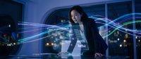 Young Asian businesswoman analyzing holographic data visualization in modern office environment at night with city lights background.